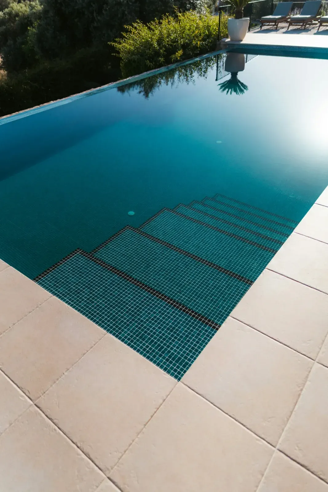 Escalones de gresite verde azulado de una piscina, con la retícula de las juntas a la vista bajo el agua