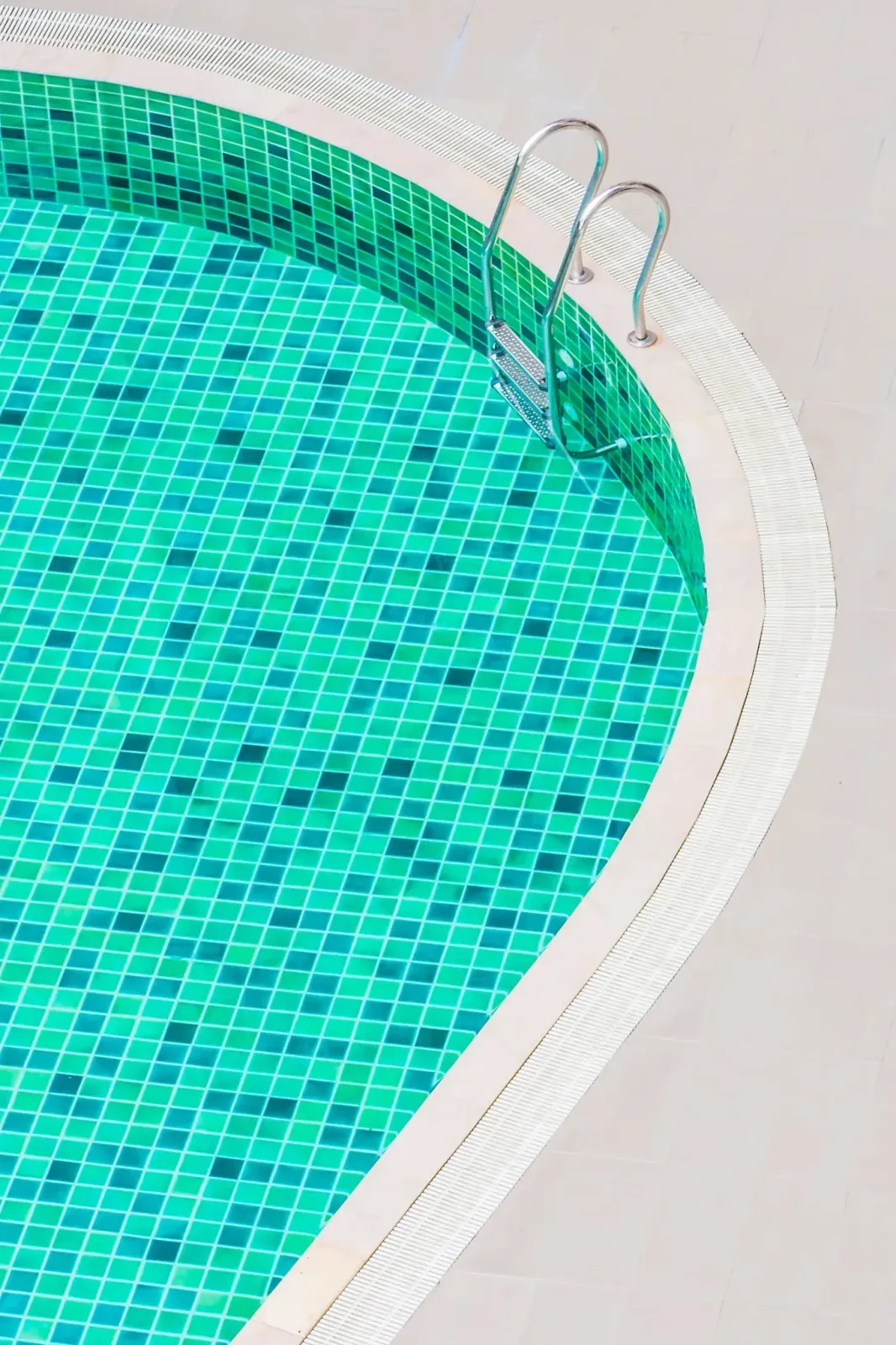 Piscina redonda de gresite verde con escalera de acero inoxidable y borde de piedra clara